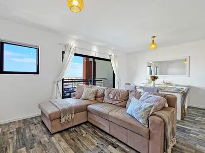 a living room with a couch and a kitchen at Sea, Canal & Mountain View, Rooftop Jacuzzi & BBQ in Cape Town
