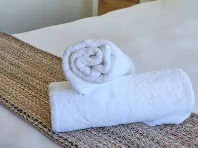 a rolled up towel sitting on top of a bed at Sea, Canal & Mountain View, Rooftop Jacuzzi & BBQ in Cape Town