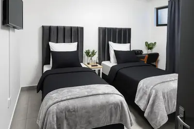 a bedroom with two beds and a table with a tv at AAA Luxury Cottages in Cape Town