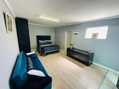 a living room with a blue couch and a bed at AAA Luxury Cottages in Cape Town