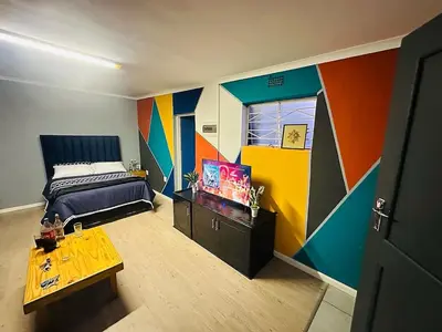a colorful bedroom with a bed and a table at AAA Luxury Cottages in Cape Town