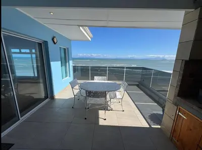 a balcony with a table and chairs and the ocean at Pips Place Penthouse 501 in Strand