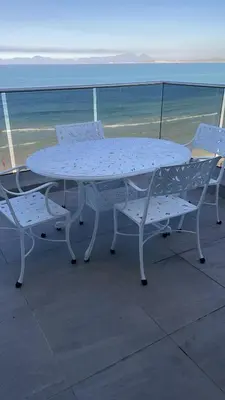 a white table and chairs on a balcony with the ocean at Pips Place Penthouse 501 in Strand