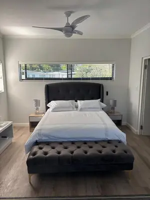 a bedroom with a large bed with a ceiling fan at 37A Modern Apartment quiet suburb mountain views in Stellenbosch