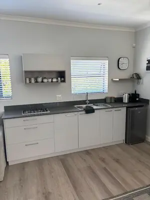 a kitchen with white cabinets and a counter top at 37A Modern Apartment quiet suburb mountain views in Stellenbosch