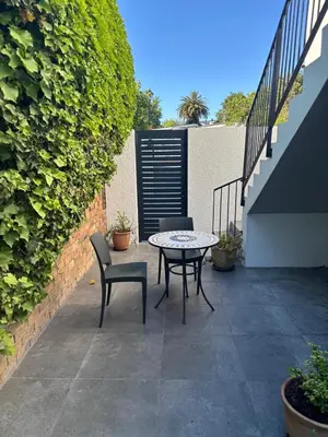 a patio with a table and chairs and a fence at 37A Modern Apartment quiet suburb mountain views in Stellenbosch