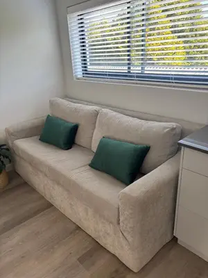 a living room with a couch with two green pillows at 37A Modern Apartment quiet suburb mountain views in Stellenbosch
