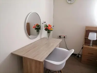 a table with a vase of flowers and a mirror at Mimosa House Double Room in Brackenfell