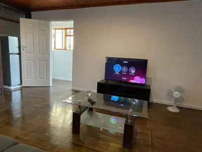 a living room with a tv and a glass table at AAA Luxury Homes Goodwood Cpt in Elsiesrivier