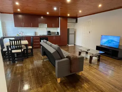 a living room with a couch and a tv and a kitchen at AAA Luxury Homes Goodwood Cpt in Elsiesrivier