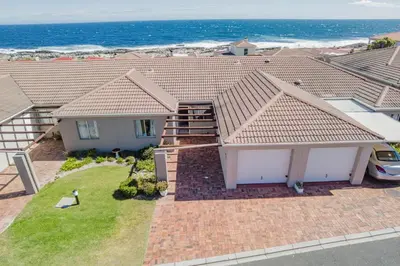 an aerial view of a house with the ocean behind it at Nostalgie - Hermanus Beach Club in Hermanus