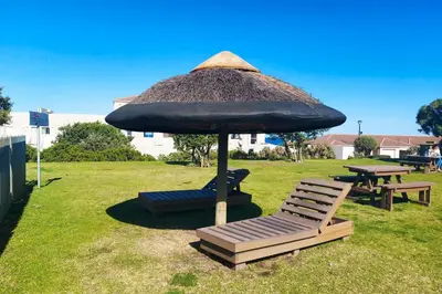 a large umbrella and two chairs and a picnic table at Nostalgie - Hermanus Beach Club in Hermanus