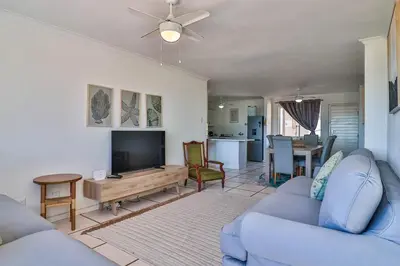 a living room with a blue couch and a tv at Nostalgie - Hermanus Beach Club in Hermanus