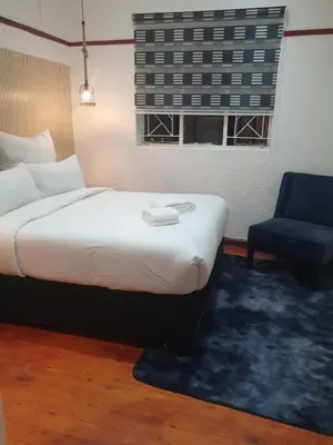 a bedroom with a bed and a chair and a window at Ludinz Self Catering Accommodation in Avondale