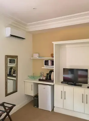 a kitchen with white cabinets and a flat screen tv at Val d'Or Estate in Franschhoek