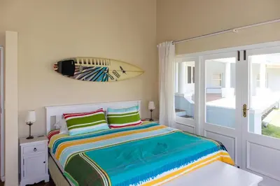 a bedroom with a bed with a surfboard on the wall at Porcupine Creek in Pringle Bay
