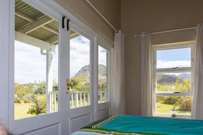 a bedroom with a bed and a door with a window at Porcupine Creek in Pringle Bay
