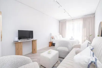 a living room with white furniture and a tv at 232 Paarl Studio With AC and Onsite Parking in Paarl