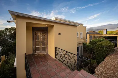 a small house with a door on a balcony at Villa Solara, 6 bedroom Vacation Villa with sea view in Gordonʼs Bay