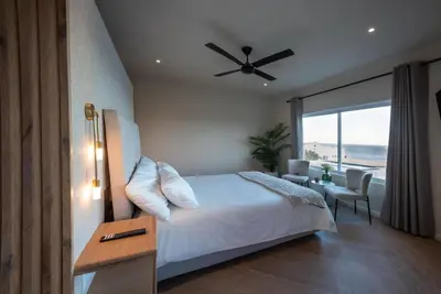 a bedroom with a bed and a view of the ocean at Villa Solara, 6 bedroom Vacation Villa with sea view in Gordonʼs Bay