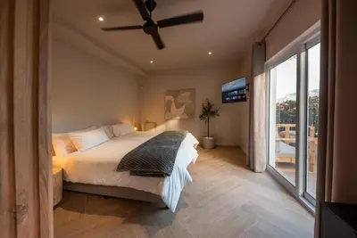 a bedroom with a bed and a ceiling fan at Villa Solara, 6 bedroom Vacation Villa with sea view in Gordonʼs Bay