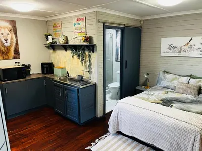a bedroom with a bed and a bathroom with a sink at Cross Road Cabin in Cape Town