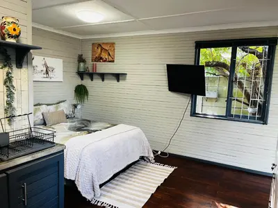 a room with a bed and a tv in a room at Cross Road Cabin in Cape Town