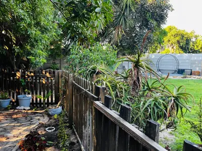 a wooden fence with plants in a yard at Cross Road Cabin in Cape Town