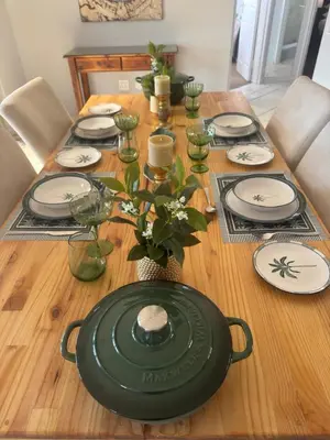 a wooden table with plates and a green centerpiece at Sunset View in Durbanville