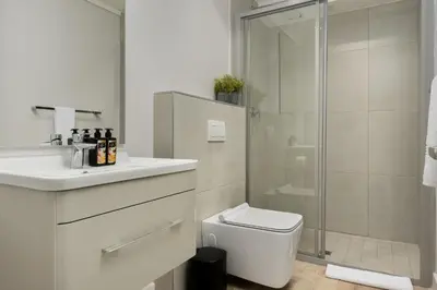 a white bathroom with a shower and a toilet at Burmeister Modern 2-Bedroom w/ Views Milnerton in Cape Town