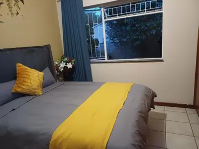 a bedroom with a bed with a yellow blanket and a window at Oakway Guest House 2 in Kuilsrivier