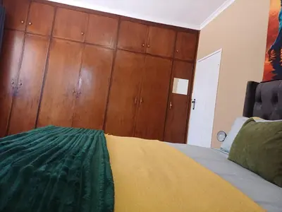a bedroom with a bed and wooden cabinets at Oakway Guest House 2 in Kuilsrivier