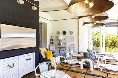 a living room with a table and chairs and a dining room at The Bay Cottage in Pringle Bay