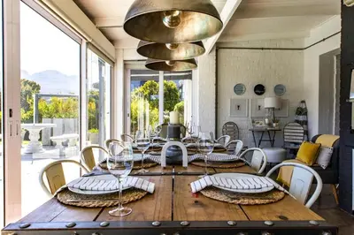 a dining room with a large wooden table and chairs at The Bay Cottage in Pringle Bay