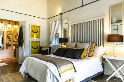 a bedroom with a large white bed with yellow pillows at The Bay Cottage in Pringle Bay