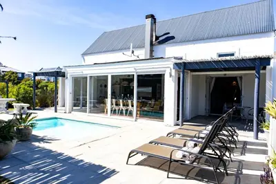 a house with a swimming pool and a patio at The Bay Cottage in Pringle Bay