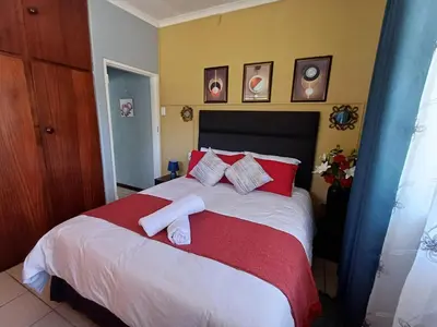 a bedroom with a large bed with red and white pillows at OakwayGuestSuit2 Private 1 Bed Kitchen Bath Aircon in Kuilsrivier