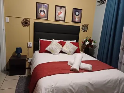 a bedroom with a large bed with red pillows at OakwayGuestSuit2 Private 1 Bed Kitchen Bath Aircon in Kuilsrivier