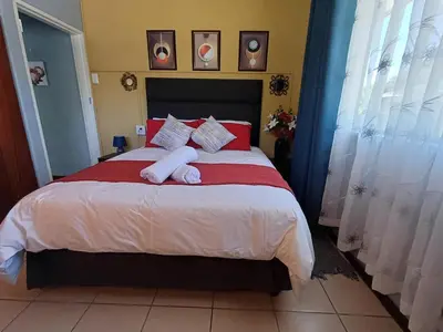 a bedroom with a large bed with red and white pillows at OakwayGuestSuit2 Private 1 Bed Kitchen Bath Aircon in Kuilsrivier