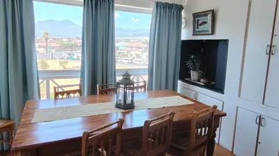 a dining room with a table and a large window at Windy Corner Luxury Apartment in Gordonʼs Bay