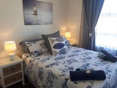 a bedroom with a blue and white bed with pillows at Windy Corner Luxury Apartment in Gordonʼs Bay