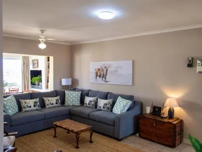 a living room with a blue couch and a table at Windy Corner Luxury Apartment in Gordonʼs Bay