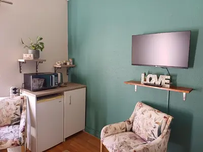 a living room with two chairs and a tv at 7th Heaven Guest Unit in Paarl