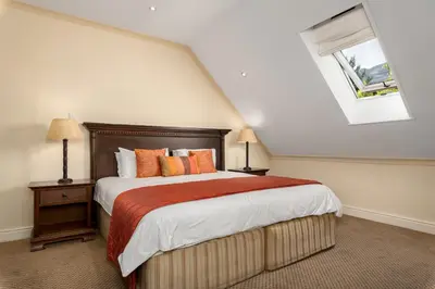 a bedroom with a bed with orange pillows and a window at Gable Manor by Neighbourgood in Franschhoek