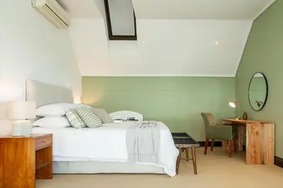 a bedroom with a bed and a table and a mirror at Manor at Longridge in Helderberg