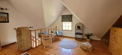 an attic room with a table and a window at Clarents Cottage in Somerset West