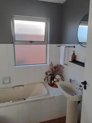 a bathroom with a tub and a sink and a window at Central 3rd Floor Durbanville Apartment in Durbanville