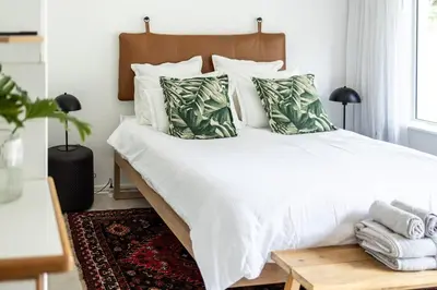 a bedroom with a bed with white sheets and pillows at Private Garden Flat in Die Boord with Secure Parking in Stellenbosch