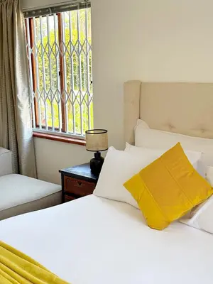 a bed with a yellow pillow and a window at Olly-Pops Cottage in Tygerberg Hills