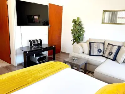 a living room with a bed and a couch at Olly-Pops Cottage in Tygerberg Hills